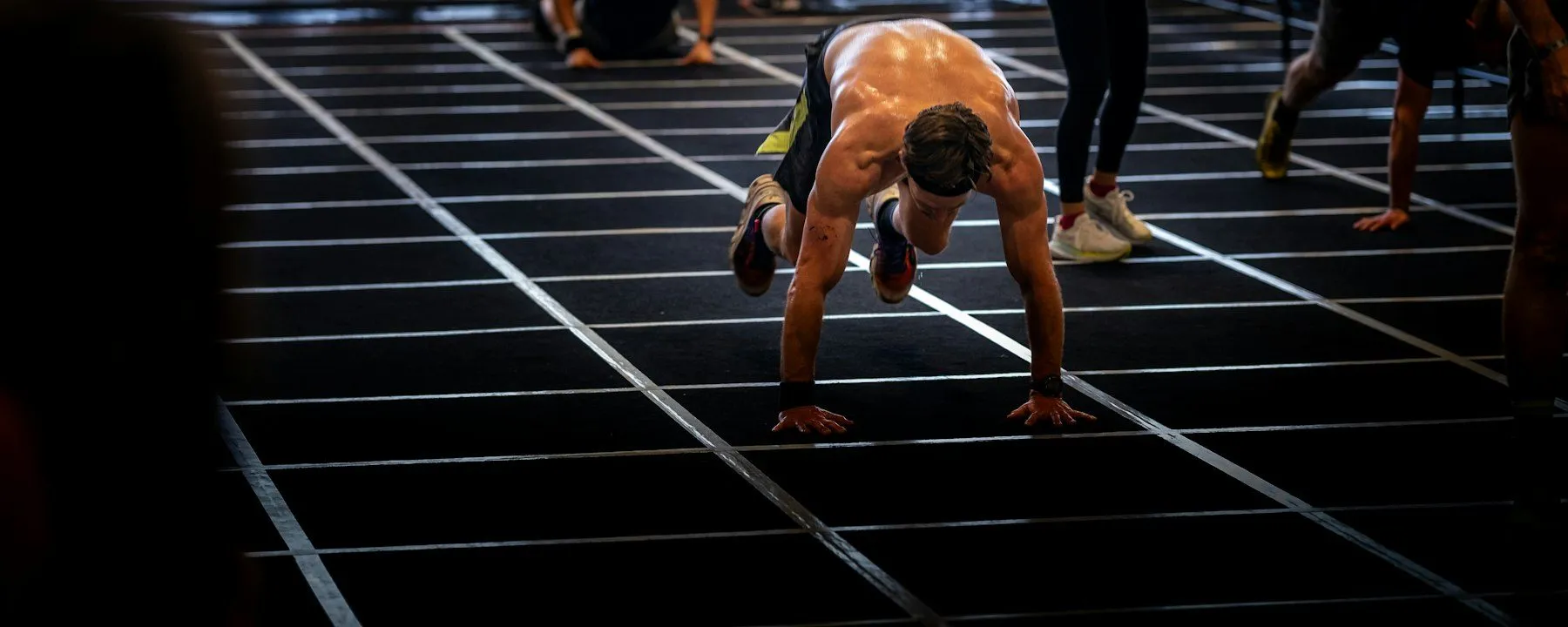 Atleta haciendo burpees sobre una pista de competición en un pabellón